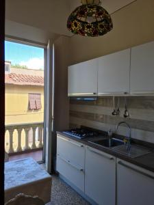 Una cocina con gabinetes blancos y un fregadero y una ventana. en Appartamento Angela, en Pisa