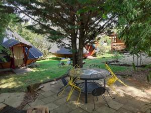 a patio with a table and chairs under a tree at Tipis Du Petit Buisson in Saint-Antonin-de-Lacalm