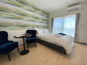 石垣島にあるHOTEL Ishigakijima 2020のベッド、テーブル、椅子が備わるホテルルームです。