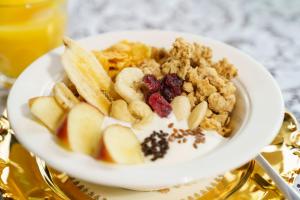 a bowl of cereal and fruit and a bowl of milk at Tante ALMA's Bonner Hotel in Bonn