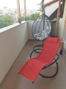 a red chair and a basket on a balcony at Cosy Charming Apartment in Blagoevgrad