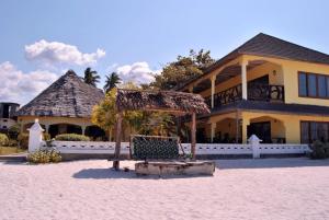 a house on the beach with a chair in front of it at White Sands in Paje