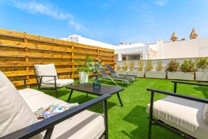 a patio with chairs and a table on the grass at Genteel Home San Antonio in Cádiz