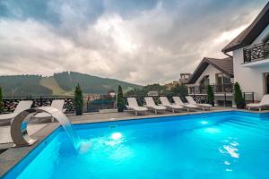 a swimming pool with chairs and a house at Chalet Fomich in Bukovel