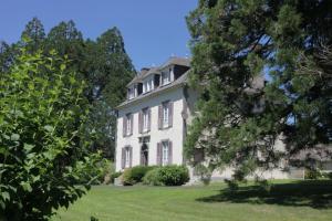 ein großes weißes Haus mit Bäumen im Vordergrund in der Unterkunft HOSTELLERIE LA BRUYERE in Chalvignac