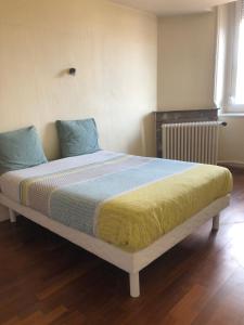 a bed with a yellow and blue blanket and a window at L’ÉMERAUDE 2 in Chalons en Champagne