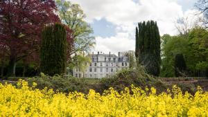 a building in the middle of a garden with yellow flowers at Les Ecuries du Château de Brumare in Brestot