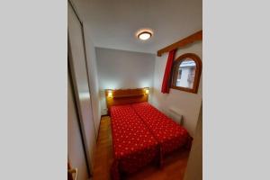 Cama roja en una habitación pequeña con espejo en Appartement en plein coeur du Queyras - Les Granges d'Arvieux en Arvieux