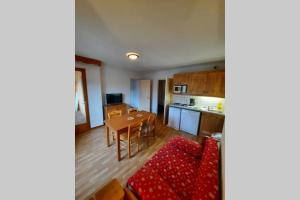 a living room with a red couch and a kitchen at Appartement en plein coeur du Queyras - Les Granges d'Arvieux in Arvieux