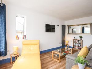 uma sala de estar com um sofá e uma televisão em Ty Coets Coach House em Caernarfon