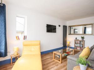a living room with a couch and a tv at Ty Coets Coach House in Caernarfon