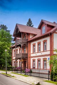 a large red brick house with a black fence at Lawenda Apartamenty Boutique in Kudowa-Zdrój