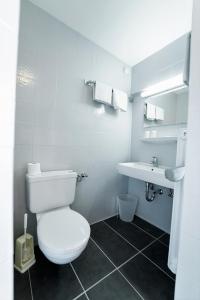 a white bathroom with a toilet and a sink at Ihre Pension in Amerang in Amerang