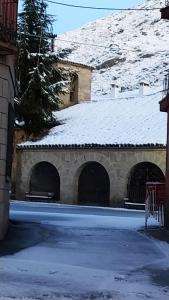 un edificio con techo cubierto de nieve y bancos en Casa Rural la Cancha I, en Navalacruz