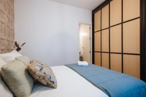 een slaapkamer met een groot wit bed met blauwe kussens bij Feijóo Suite Apartment in Sevilla +11 foto's