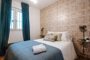 een slaapkamer met een groot bed met blauwe gordijnen bij Feijóo Suite Apartment in Sevilla