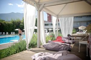 a group of beds under a pavilion next to a pool at Hotel Luise in Riva del Garda