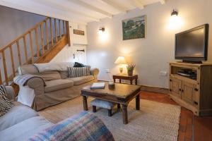 a living room with a couch and a tv at Bankside Cottage in Alstonfield