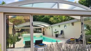 a house with a swimming pool with a glass extension at La coudraie votre maison de vacances en famille in Daumeray