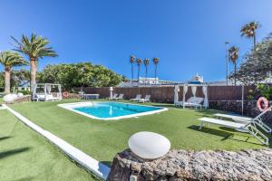 un patio trasero con piscina y césped en Villas New Lanzasuites en Playa Blanca