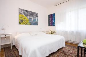 a white bedroom with a white bed and a window at Apartment Doris in Opatija