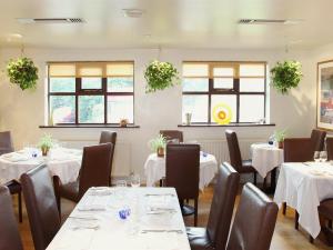 un restaurante con mesas y sillas blancas y ventanas en The Bakery Restaurant with Rooms, en Westerham