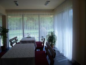 a dining room with tables and chairs and a large window at Pensiunea Mara in Deseşti