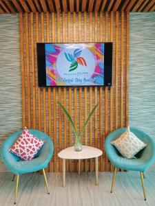 2 chaises et une table avec une télévision murale dans l'établissement Felicity Island Hotel, à Mactan