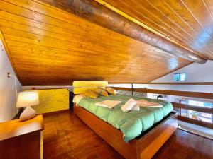 a bed in a small room with a wooden ceiling at Casa Brenzio Rustico in Consiglio di Rumo