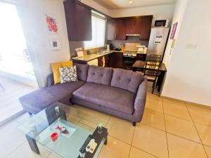 ein Wohnzimmer mit einem lila Sofa und einer Küche in der Unterkunft Promenade Breeze City Apartment in Larnaka