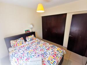Schlafzimmer mit einem Bett mit bunter Bettwäsche und Schränken in der Unterkunft Promenade Breeze City Apartment in Larnaka