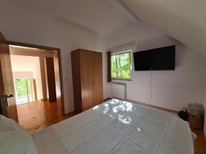 Un dormitorio con una gran cama blanca y un televisor de pantalla plana. en Casa Bella, en Dognecea