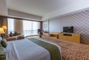 a hotel room with a bed and a flat screen tv at Wyndham Surabaya in Surabaya