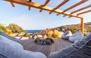 a patio with a fire pit and a view of the ocean at Villa Artisti Mykonos in Agrari