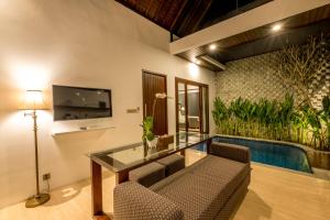 a living room with a glass table and a swimming pool at PANDAWA VILLAS SEMINYAK in Seminyak