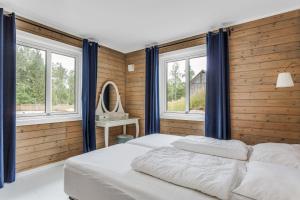 two beds in a bedroom with wooden walls and windows at Large vacationhome with a modern design in Blankered