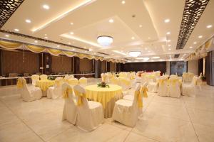 a banquet hall with yellow tables and white chairs at Genx Crescent Lucknow in Lucknow