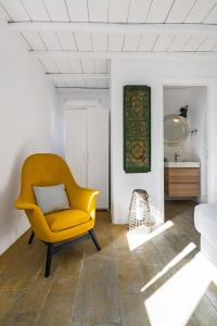 a yellow chair in a room with a mirror at Villa Artisti Mykonos in Agrari