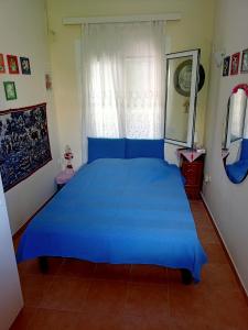 1 cama azul en un dormitorio con ventana en Lefteris BEAUTIFUL AEGINA, en Aegina Town