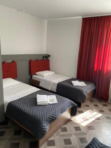 two beds in a room with red curtains at Orange Club in Zarechnyy