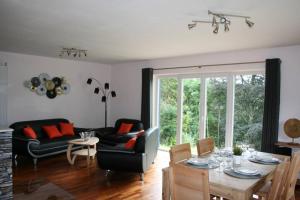 een woonkamer met een tafel en een bank bij Gîte L'à côté, bungalow plain-pied sans vis-à-vis. in Spa