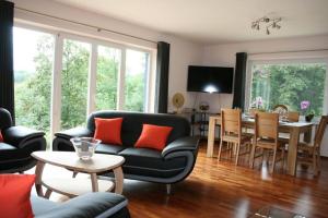 uma sala de estar com um sofá e uma sala de jantar em Gîte L'à côté, bungalow plain-pied sans vis-à-vis. em Spa