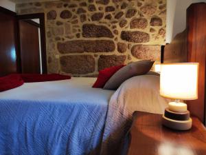 a bedroom with a bed with two lamps and a stone wall at Casa da Cuca in Campo do Gerês
