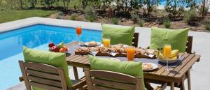 uma mesa de madeira com comida ao lado de uma piscina em Corfu Garden Villas em Corfu Town