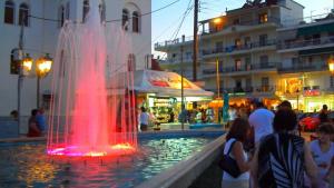 a fountain in a city with people standing around it at AlenStudios in Paralia Katerinis