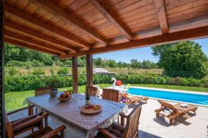 eine Terrasse mit einem Tisch und Stühlen sowie einem Pool in der Unterkunft Villa Madonnina in Manjadvorci