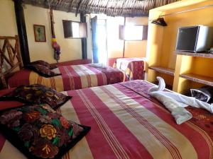 a hotel room with two beds and a tv at The Pickled Onion Eco-Boutique B&B in Santa Elena