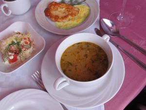 una mesa con una taza de sopa y platos de comida en Hotel Vetraz, en Vitebsk