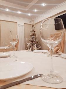 a table with wine glasses and a christmas tree at Hotel Vetraz in Vitebsk