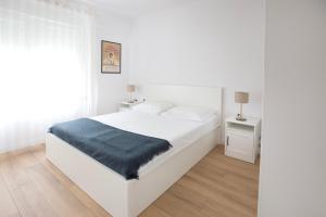 a white bedroom with a white bed with a blue blanket at Firpo: Cozy double room city centre apartment in Vis